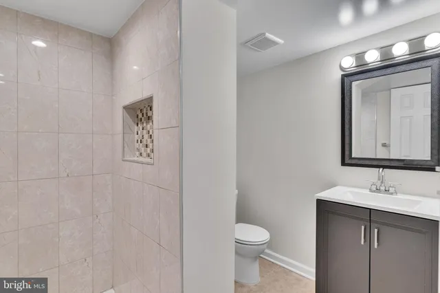 a bathroom with a toilet sink vanity and mirror