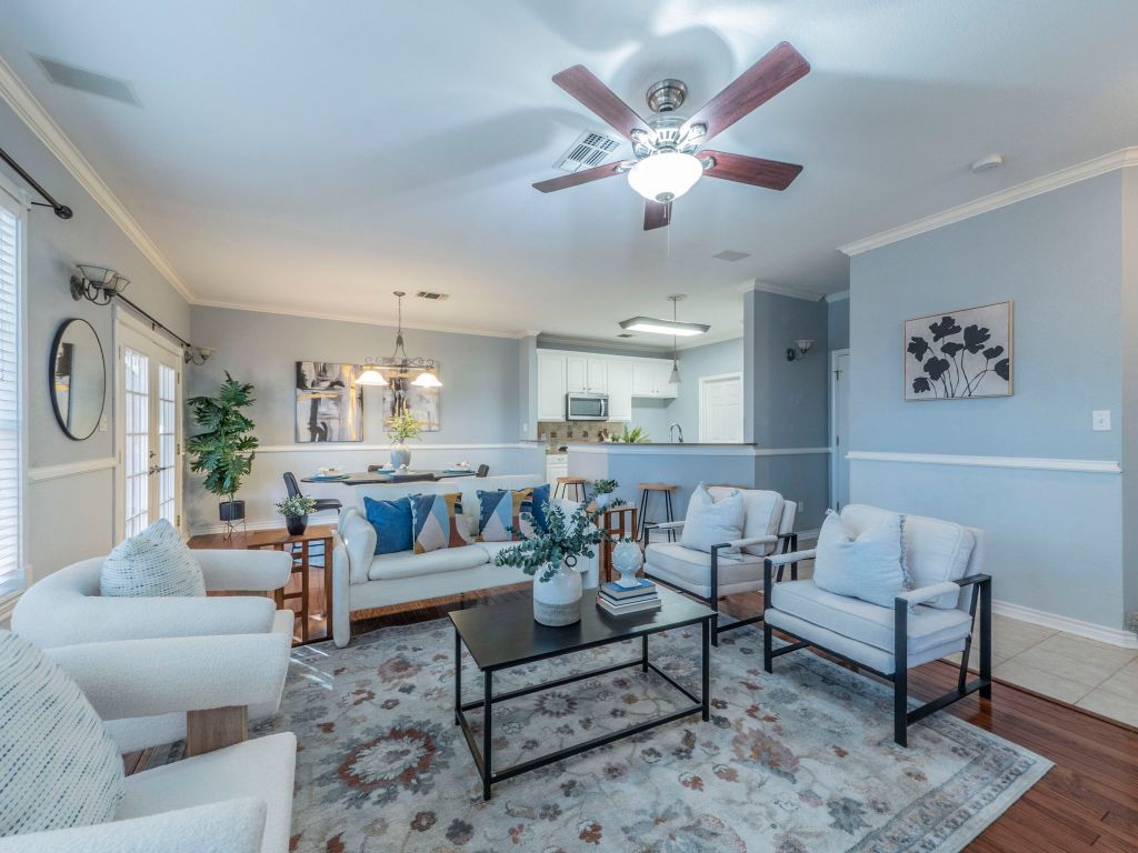 Living area featuring crown molding, dark wood-style floors, a chandelier, and a ceiling fan