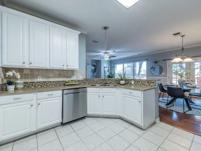 a kitchen with granite countertop white cabinets white stainless steel appliances with a dining table and chairs