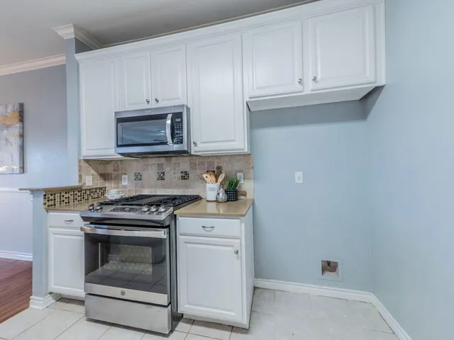 a kitchen with granite countertop white cabinets and stainless steel appliances