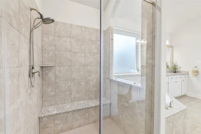 a large bathroom with a granite countertop double vanity sink a mirror and a bathtub
