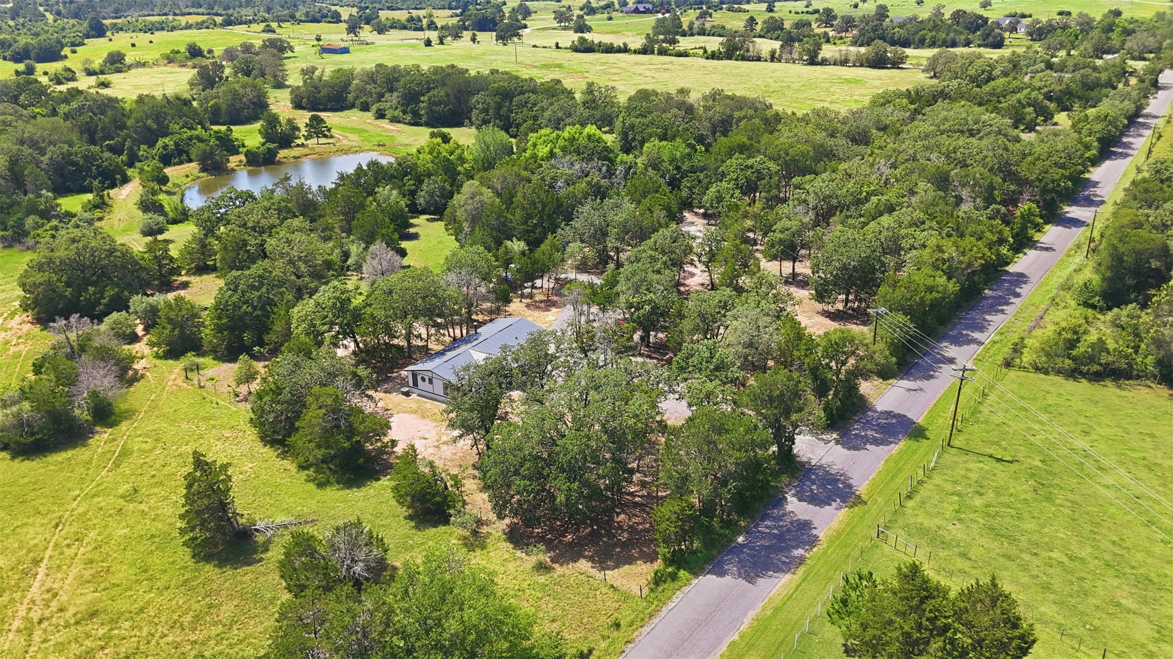 154 Antioch Road Smithville, TX 78957 - Photo 26 of 32 This residence nestled amongst verdant fields and mature trees. *Pond is not part of this property*