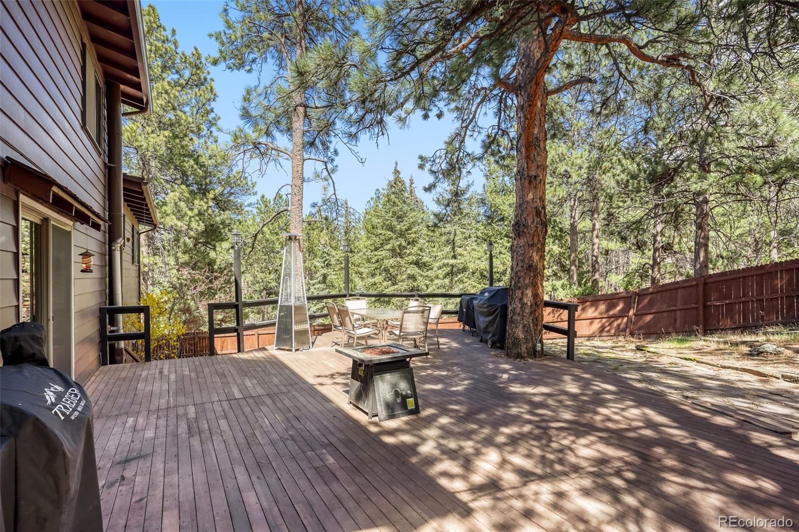 3518 South Saddle Road Evergreen, CO 80439 - Photo 18 of 27 a view of a patio with table and chairs next to a yard with wooden fence