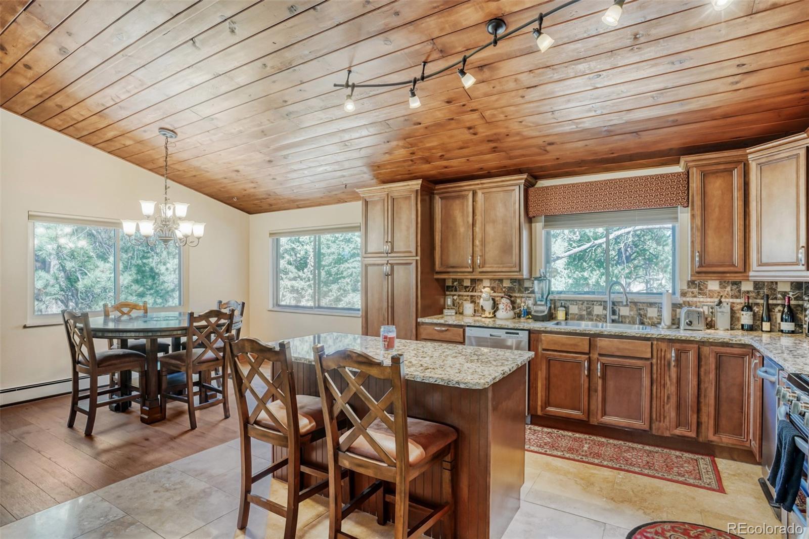 3518 South Saddle Road Evergreen, CO 80439 - Photo 7 of 27 a dining hall with stainless steel appliances granite countertop wooden cabinets a dining table and chairs with the wooden floor