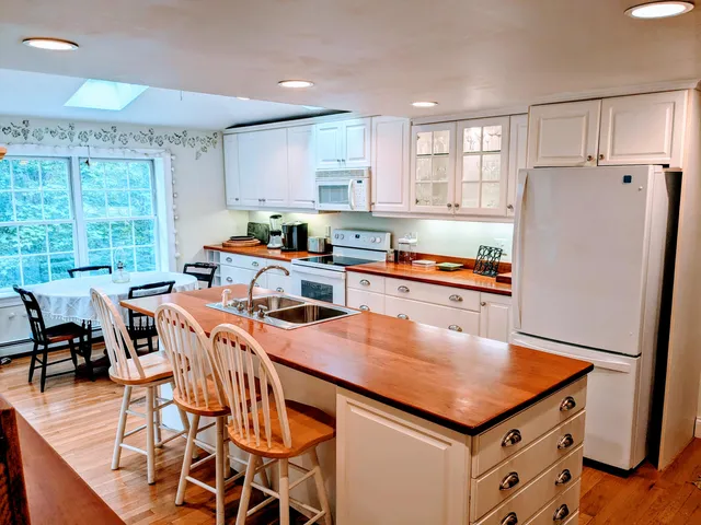 a kitchen with stainless steel appliances a table chairs refrigerator and window