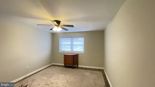 an empty room with chandelier fan and windows