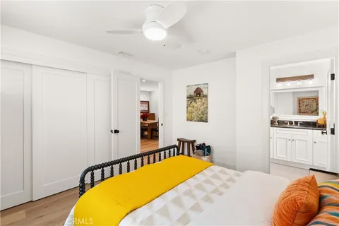 a bedroom with a bed a dresser and painting on the wall