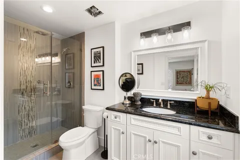 a bathroom with a granite countertop sink mirror toilet and shower