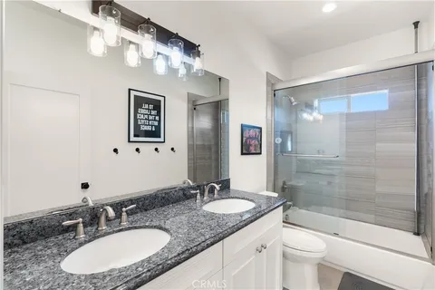 a bathroom with a granite countertop sink a toilet a mirror and shower