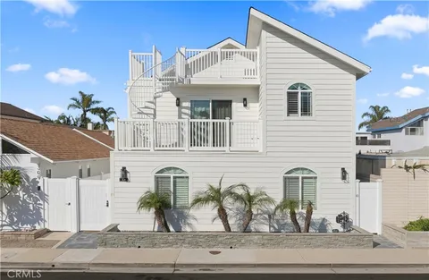 a view of a white house with two chairs and potted plants
