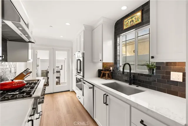 a kitchen with stainless steel appliances a sink a stove and a wooden floors