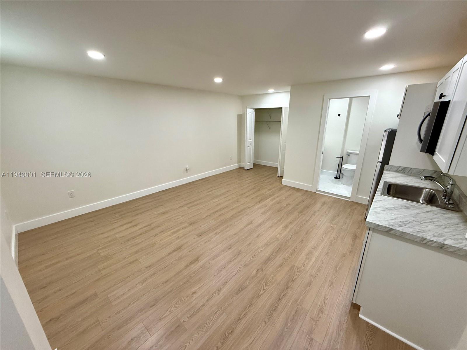 2120 Southwest 83rd Avenue Miami, FL 33155 - Photo 5 of 8 an empty room with wooden floor and mirror