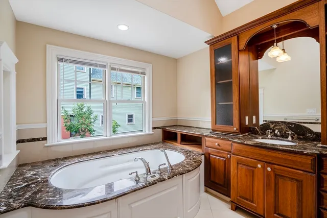 a bathroom with a granite countertop tub sink and mirror
