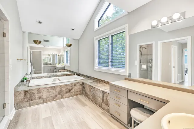 a spacious bathroom with a tub sink and mirror