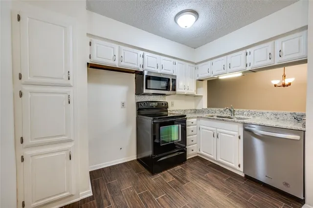 a kitchen with granite countertop a refrigerator and a stove top oven