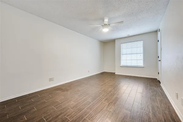an empty room with wooden floor chandelier fan and windows