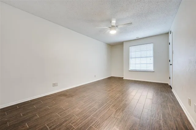 an empty room with wooden floor chandelier fan and windows
