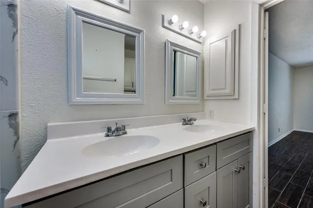 a bathroom with double vanity sink a mirror and a bathtub