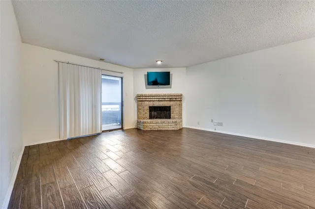 a view of a livingroom with wooden floor and a fireplace