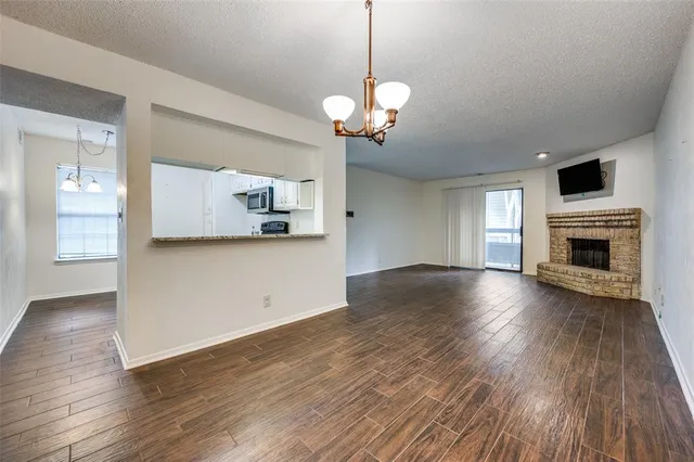 a view of a livingroom with wooden floor and a kitchen