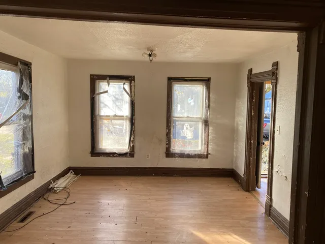 a view of an empty room with wooden floor and a window