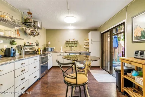a kitchen with stainless steel appliances kitchen island granite countertop a table chairs in it and wooden floors