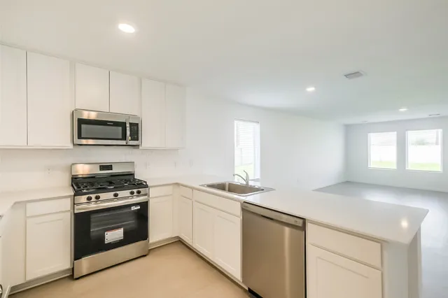 a kitchen with granite countertop a stove sink and microwave
