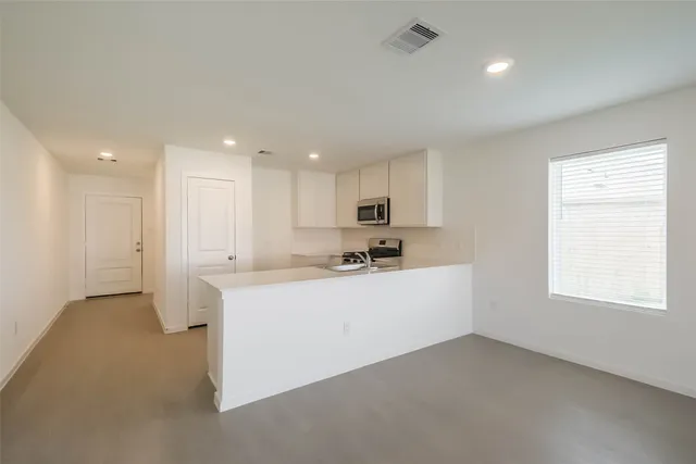 a view of a kitchen with center island stainless steel appliances wooden floor and window