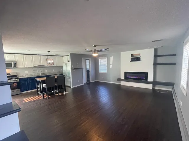 a view of a room with wooden floor and a kitchen