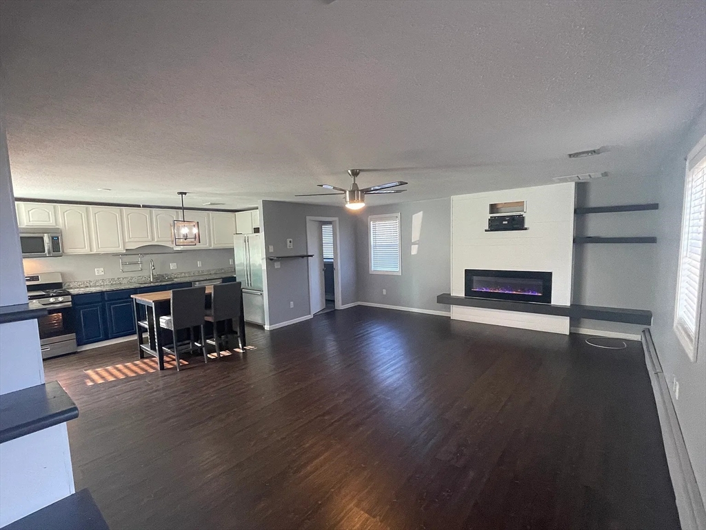 a view of a room with wooden floor and a kitchen