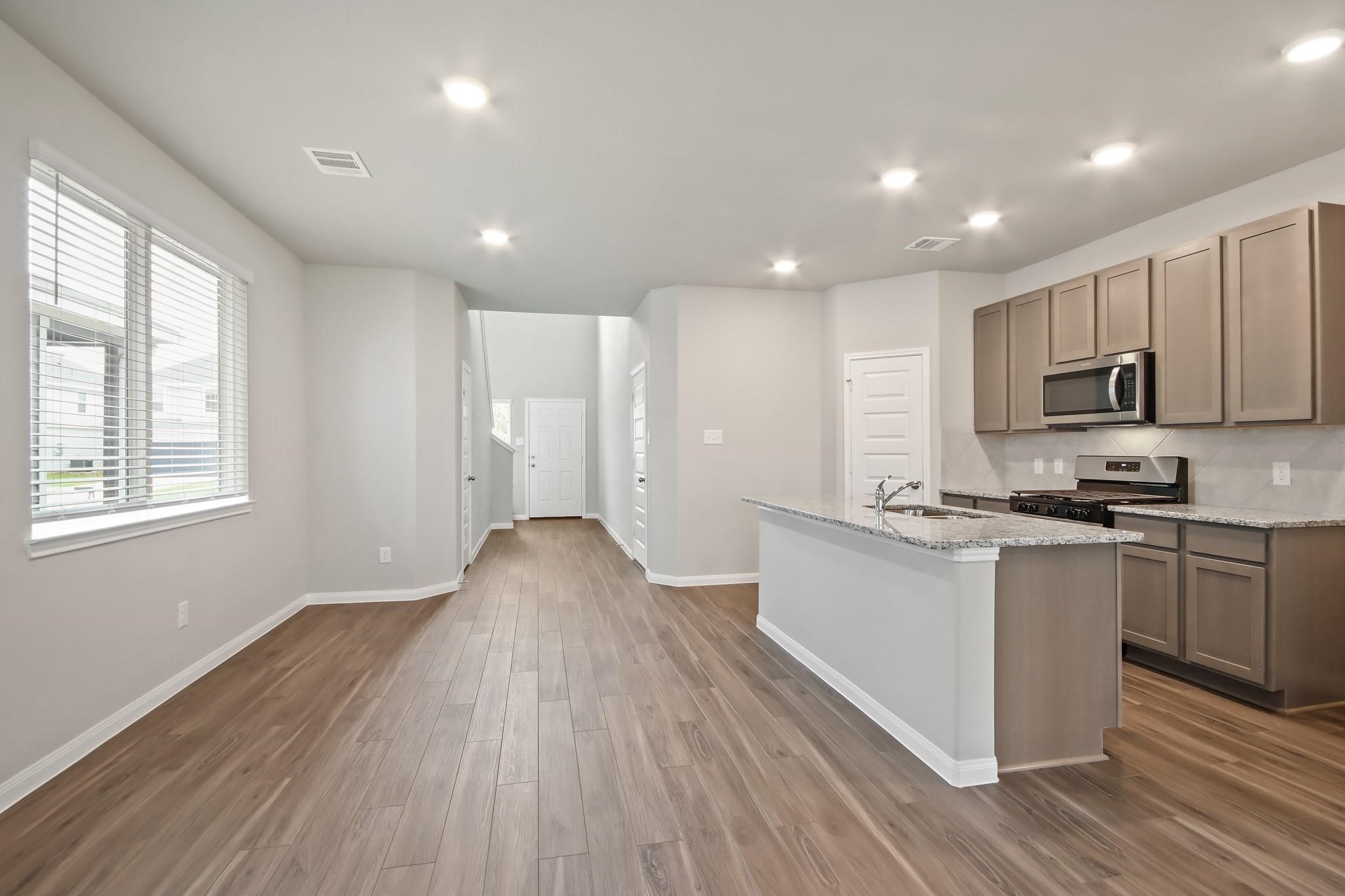 2416 Bluefish Court Conroe, TX 77384 - Photo 3 of 45 a kitchen with stainless steel appliances granite countertop a stove a sink and white cabinets with wooden floor