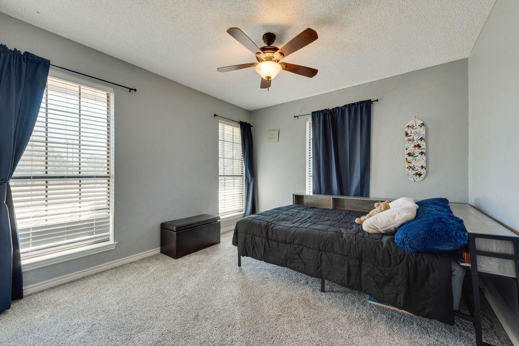 83 Crown Road Willow Park, TX 76087 - Photo 13 of 35 Neutral wall color, ceiling fan with light fixture, two windows with blinds, and light-toned carpeting