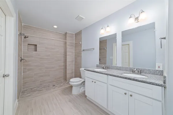 a bathroom with a granite countertop sink toilet a large mirror a glass door shower and a mirror