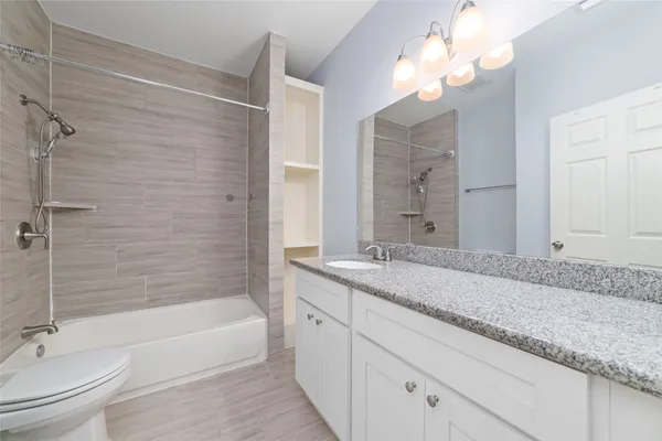 a bathroom with a granite countertop bathtub a sink and a mirror