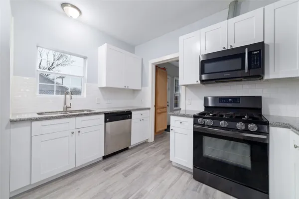a kitchen with stainless steel appliances granite countertop a stove a microwave and wooden cabinets