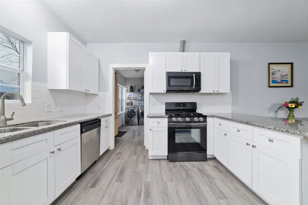 a kitchen with granite countertop a stove top oven a sink dishwasher and a refrigerator with wooden floor