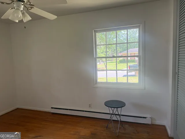 an empty room with a window and chandelier fan