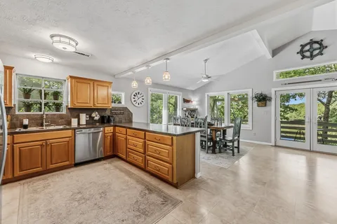 a kitchen with stainless steel appliances granite countertop a refrigerator a sink dishwasher and white cabinets with wooden floor