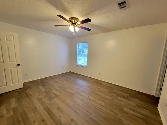 a view of empty room with wooden floor and fan