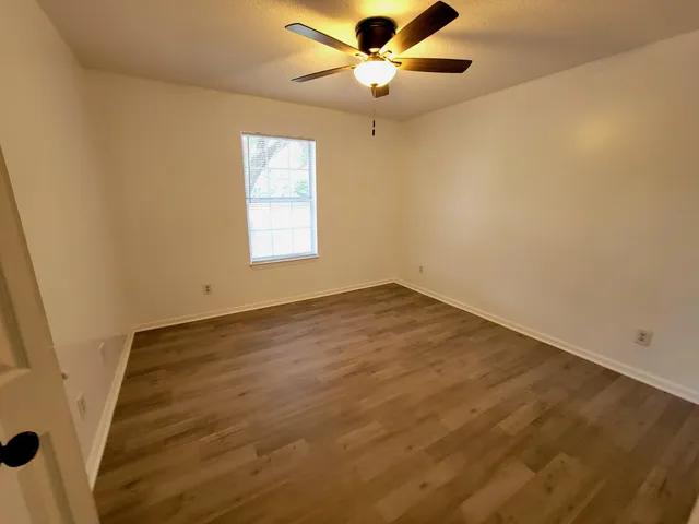 an empty room with a window and a ceiling fan