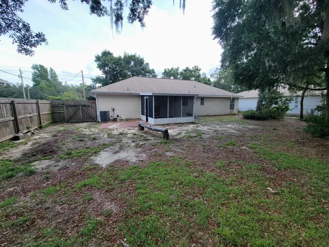 a backyard of a house with table and chairs under an umbrella