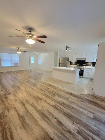 a view of a kitchen with furniture a ceiling fan and wooden floor