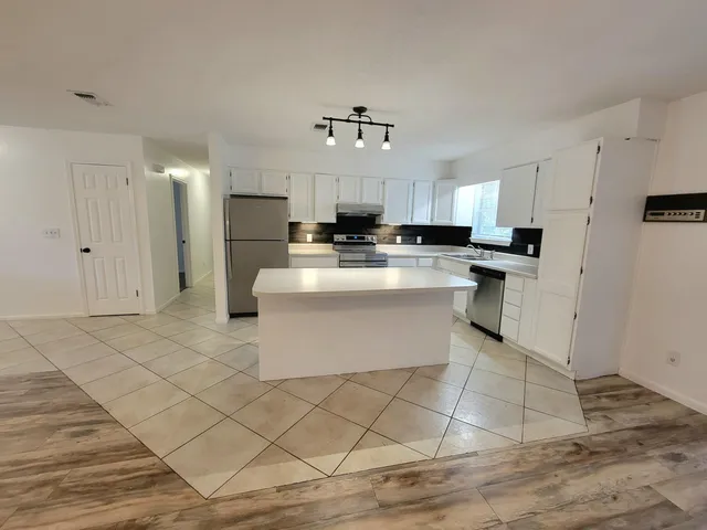 a kitchen with kitchen island granite countertop a stove oven and white cabinets