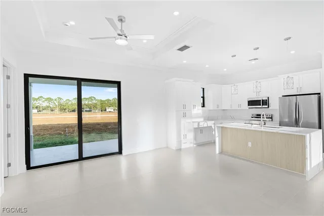a large white kitchen with a large window a sink and stainless steel appliances