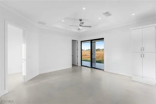 an empty room with chandelier fan and windows