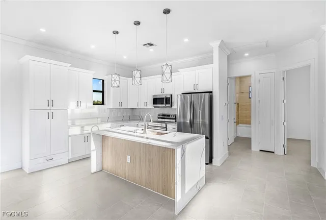 a kitchen with stainless steel appliances granite countertop a refrigerator oven a sink and white cabinets with wooden floor