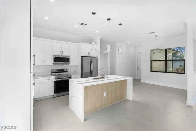 a kitchen with stainless steel appliances a stove a refrigerator a oven a sink and white cabinets