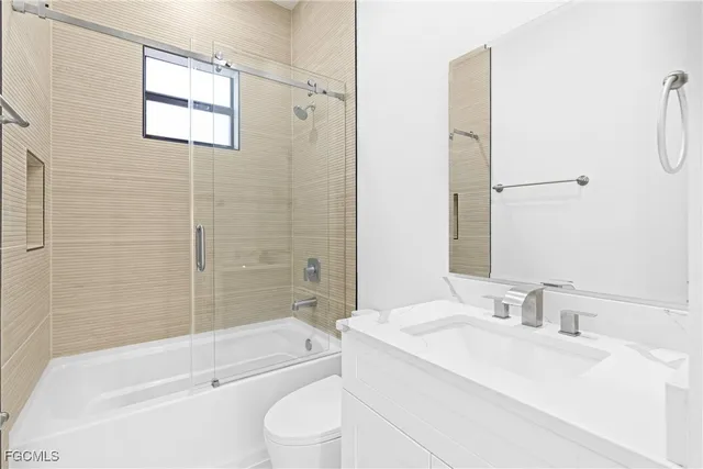 a bathroom with a granite countertop bathtub shower sink vanity and toilet