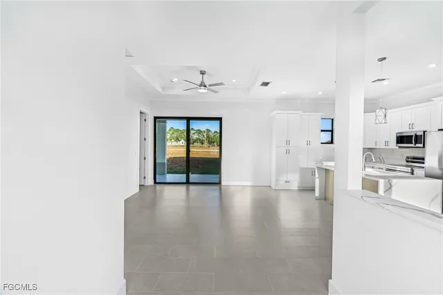 a view of an empty room and kitchen view with wooden floor