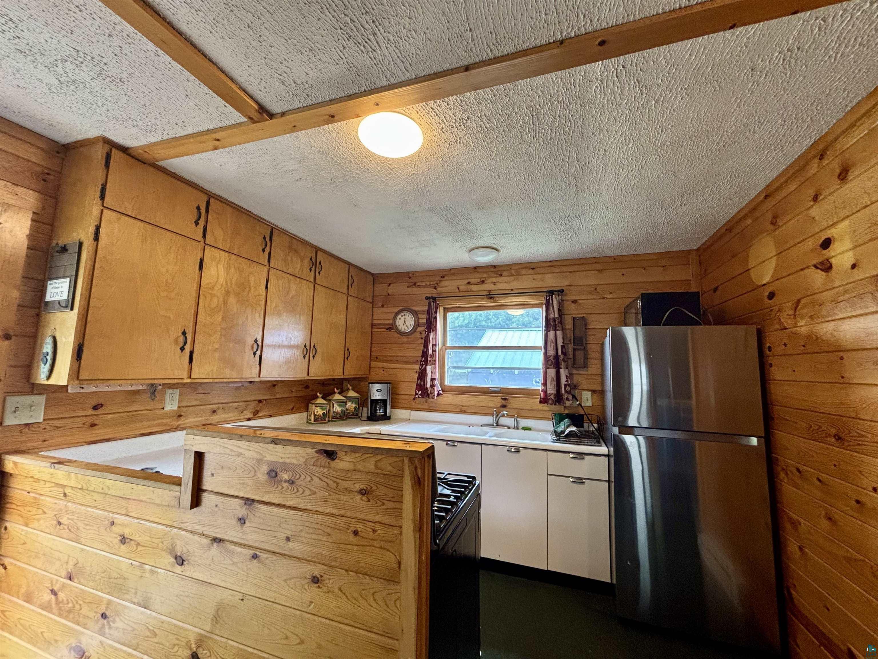 9724 State Highway 1 Isabella, MN 55607 - Photo 5 of 21 Kitchen with freestanding refrigerator, wooden walls, light countertops, a sink, and black range with gas stovetop